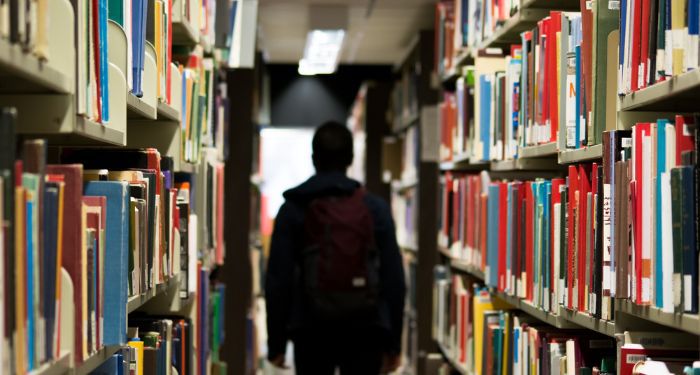 high schooler walking between book stacks