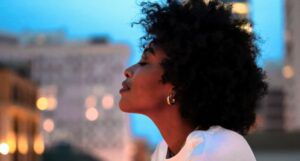 black woman lifting her head against city backdrop