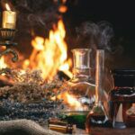 glass decanters filled with colorful liquid next to a candelabra with lit candles and a fire burning in the background