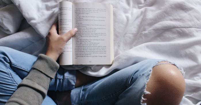 a photo of someone reading a book with the cover curled under